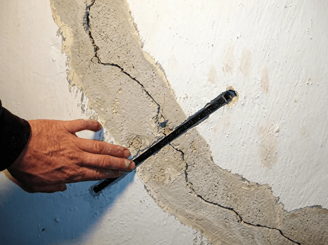 A wall with a large crack is being inspected by a professional in Milwaukee, WI